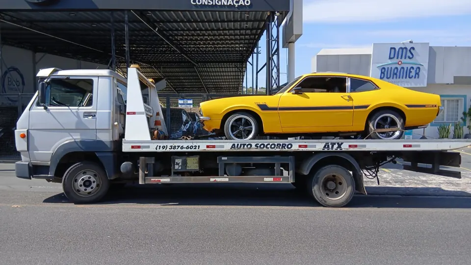 Caminhão guincho ATX transportando um carro amarelo na plataforma
